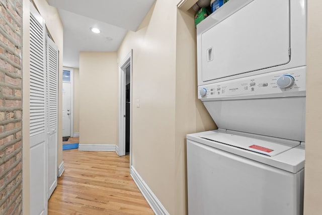 laundry room with recessed lighting, laundry area, baseboards, stacked washer / drying machine, and light wood-type flooring