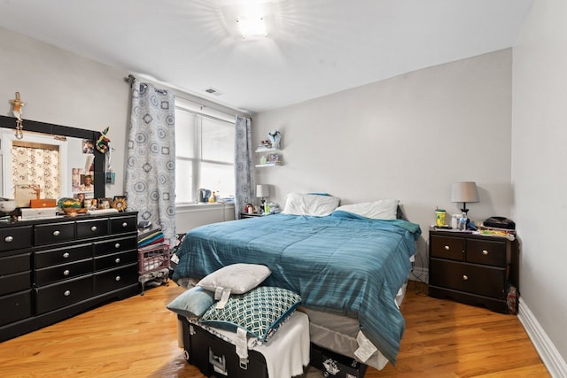 bedroom with visible vents, baseboards, and wood finished floors