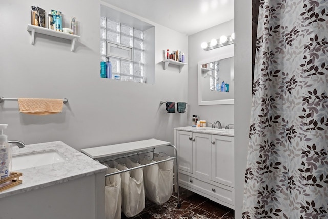 full bathroom featuring marble finish floor, a shower with curtain, two vanities, and a sink