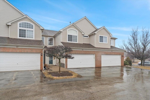 view of front of house featuring brick siding, an attached garage, driveway, and a shingled roof