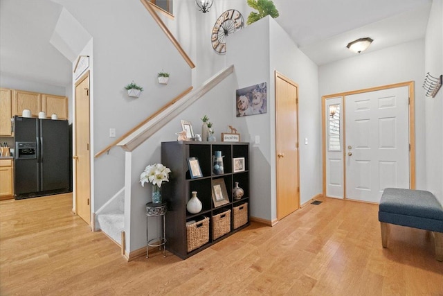 entrance foyer featuring stairs, light wood-style floors, and baseboards