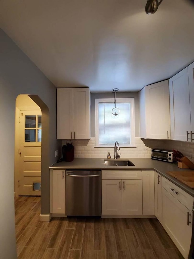 kitchen featuring dishwasher, arched walkways, a sink, and white cabinetry