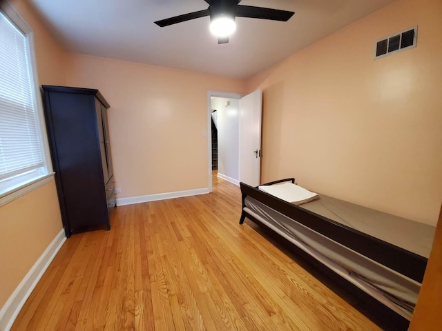 unfurnished bedroom featuring a ceiling fan, baseboards, visible vents, and light wood finished floors