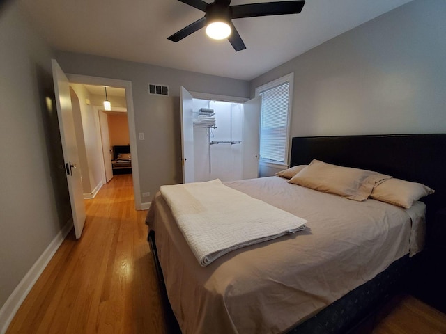 bedroom featuring ceiling fan, light wood-type flooring, visible vents, and baseboards