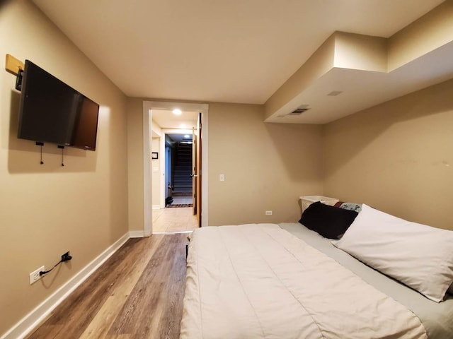 bedroom with visible vents, baseboards, and wood finished floors