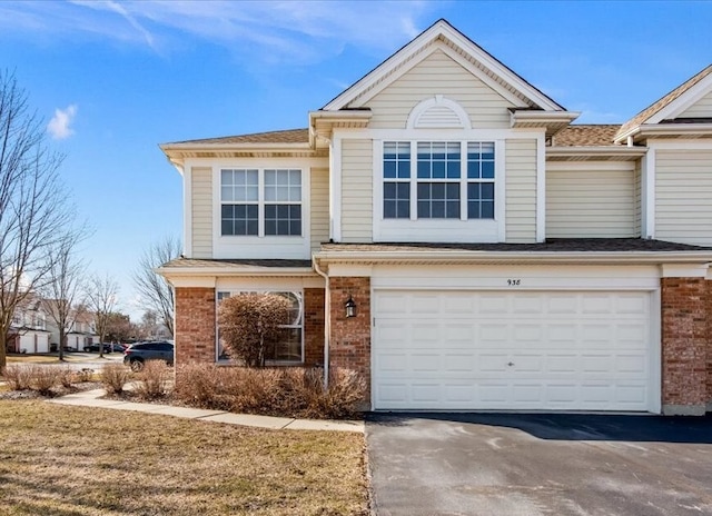 view of front of property featuring brick siding, an attached garage, and aphalt driveway