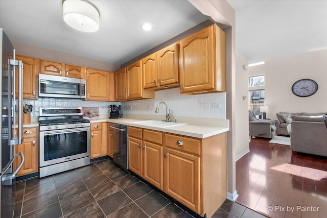 kitchen with backsplash, open floor plan, light countertops, stainless steel appliances, and a sink