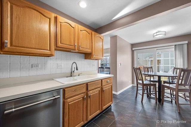 kitchen featuring backsplash, dishwasher, light countertops, and a sink