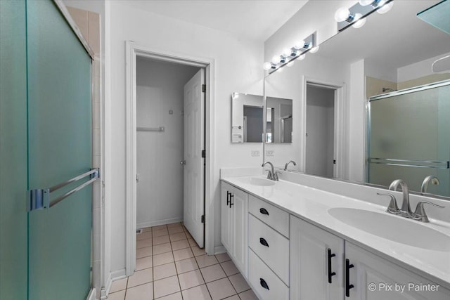 full bathroom featuring tile patterned floors, a stall shower, double vanity, and a sink