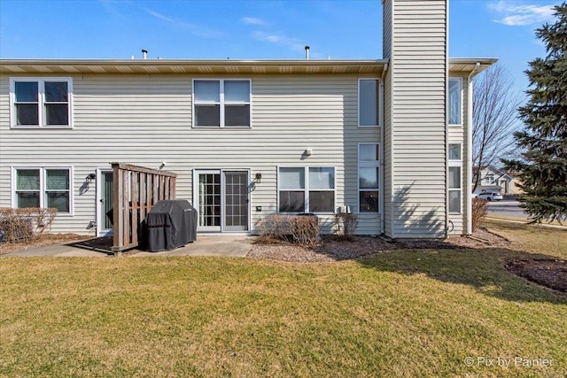 back of property featuring a patio area, a lawn, and a chimney