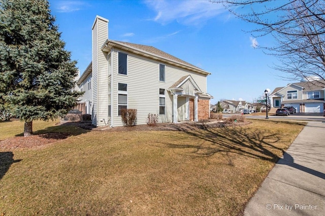 view of side of property with a yard, a residential view, and a chimney