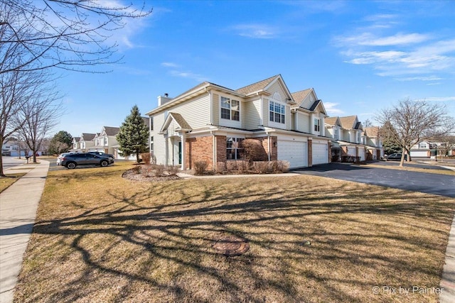 view of front of house featuring brick siding, a residential view, driveway, and an attached garage