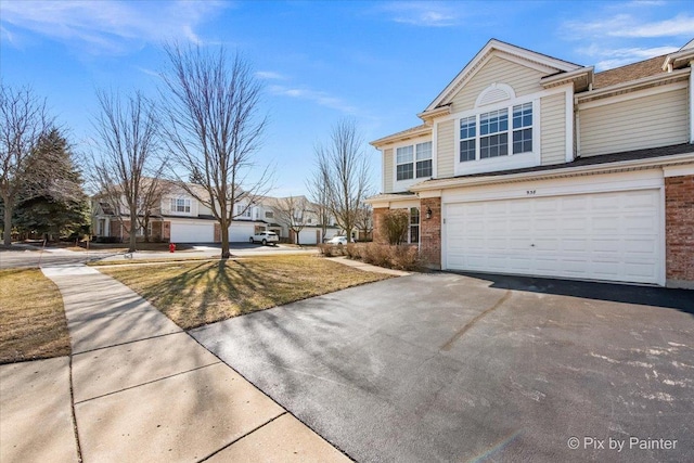 view of front of house featuring aphalt driveway, an attached garage, and brick siding