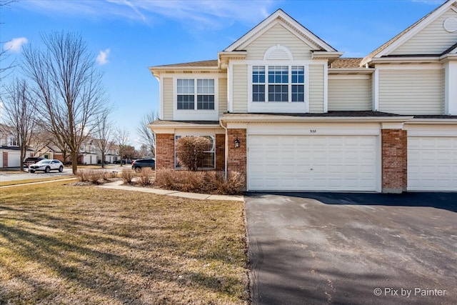 view of front of property featuring a garage, a front lawn, brick siding, and driveway