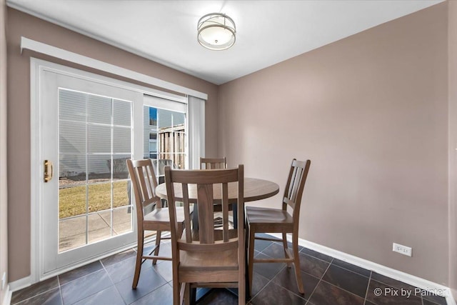 dining room featuring dark tile patterned floors and baseboards