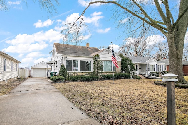 view of front of home featuring a garage, concrete driveway, a chimney, and an outdoor structure