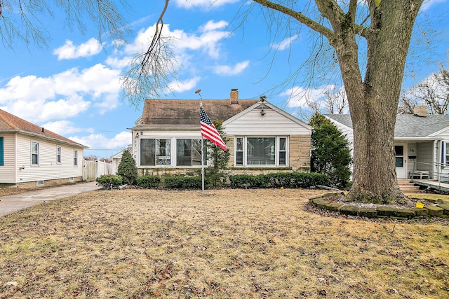 view of front of house featuring stone siding, a chimney, and fence