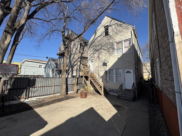 rear view of house featuring entry steps, fence, and a patio