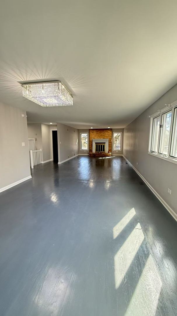 unfurnished living room featuring finished concrete flooring, a fireplace, and baseboards