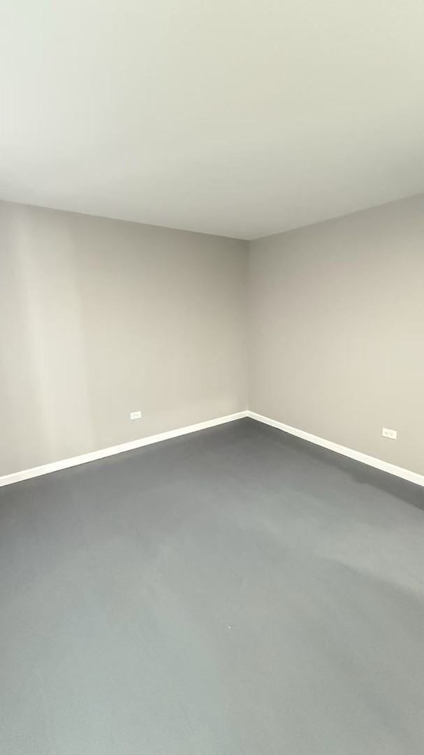 unfurnished room featuring concrete flooring and baseboards