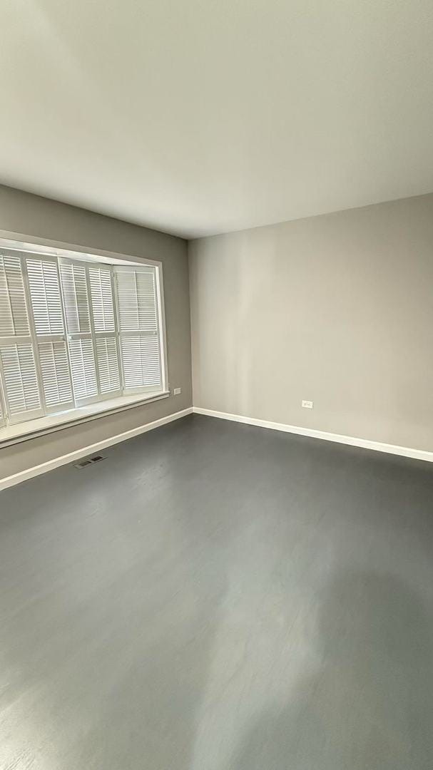 unfurnished room featuring finished concrete flooring, baseboards, and visible vents