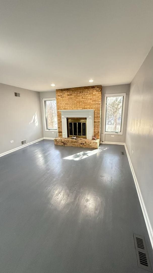 unfurnished living room featuring a fireplace, visible vents, and baseboards