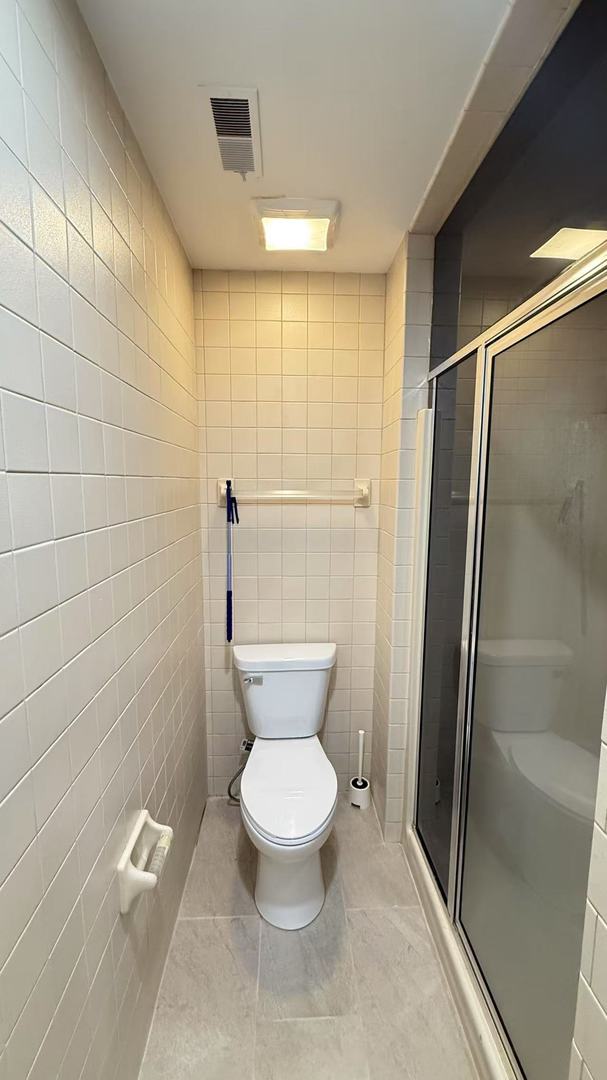 full bath with a shower stall, visible vents, tile walls, and toilet