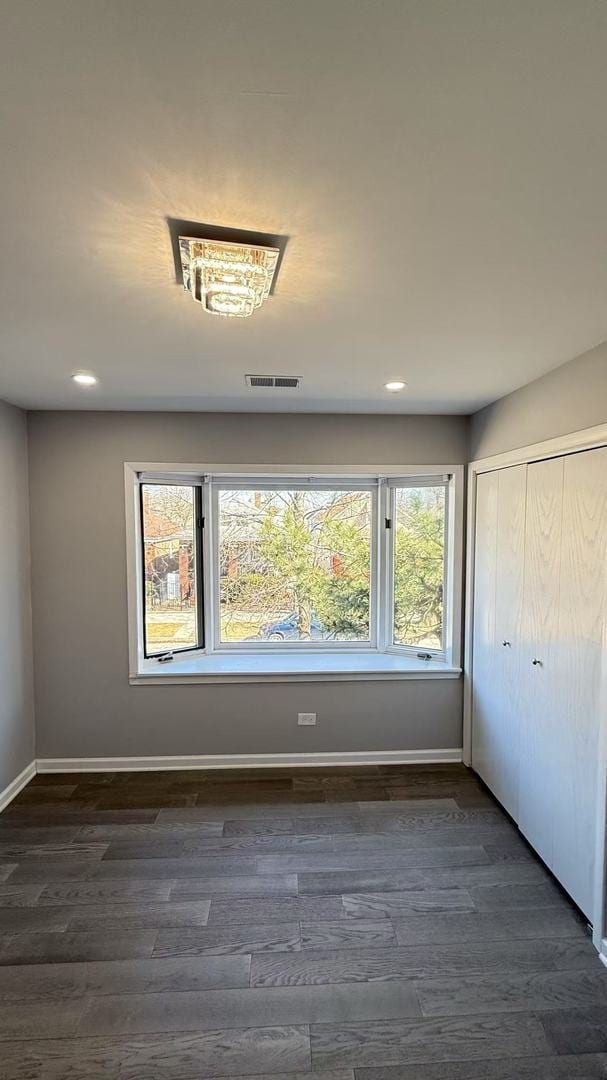 unfurnished room featuring baseboards, visible vents, and dark wood-style flooring