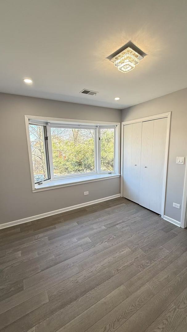 unfurnished bedroom featuring baseboards, visible vents, and wood finished floors