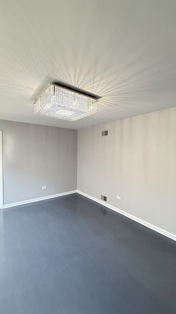 spare room featuring finished concrete floors, visible vents, and baseboards