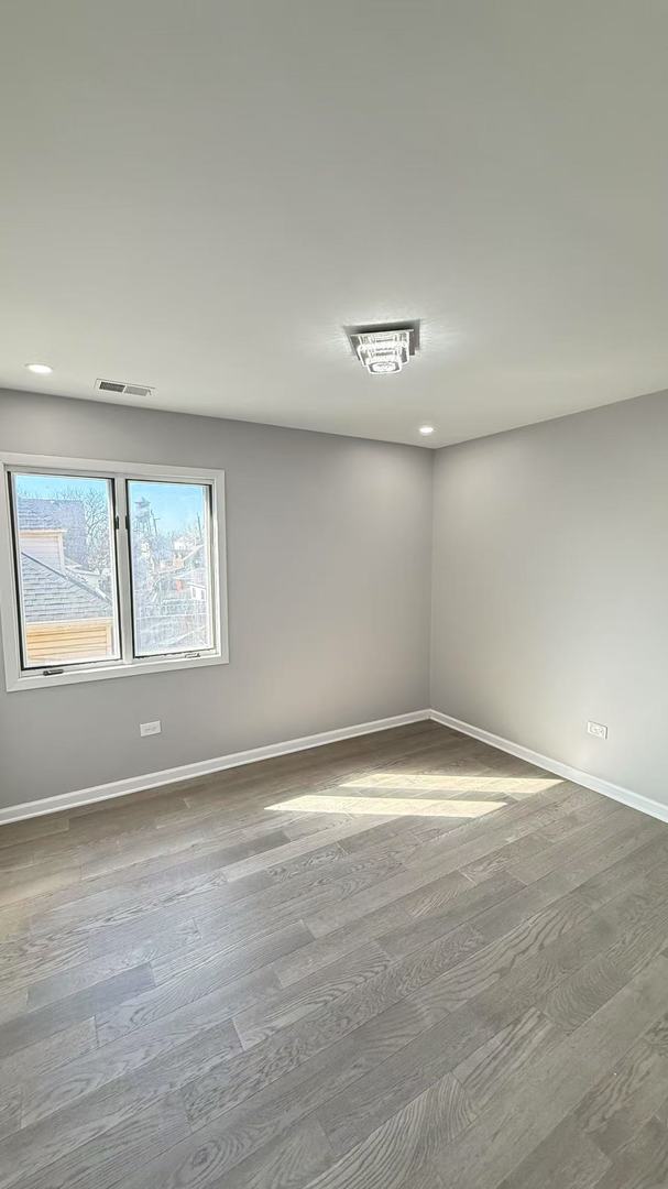 empty room with visible vents, baseboards, and wood finished floors