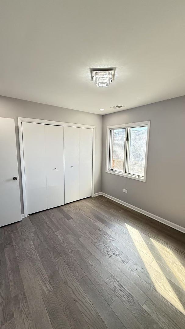 unfurnished bedroom with a closet, dark wood finished floors, and baseboards