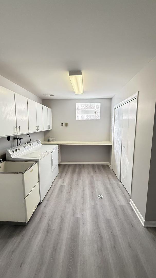 laundry room with light wood-style floors, washing machine and dryer, cabinet space, and baseboards