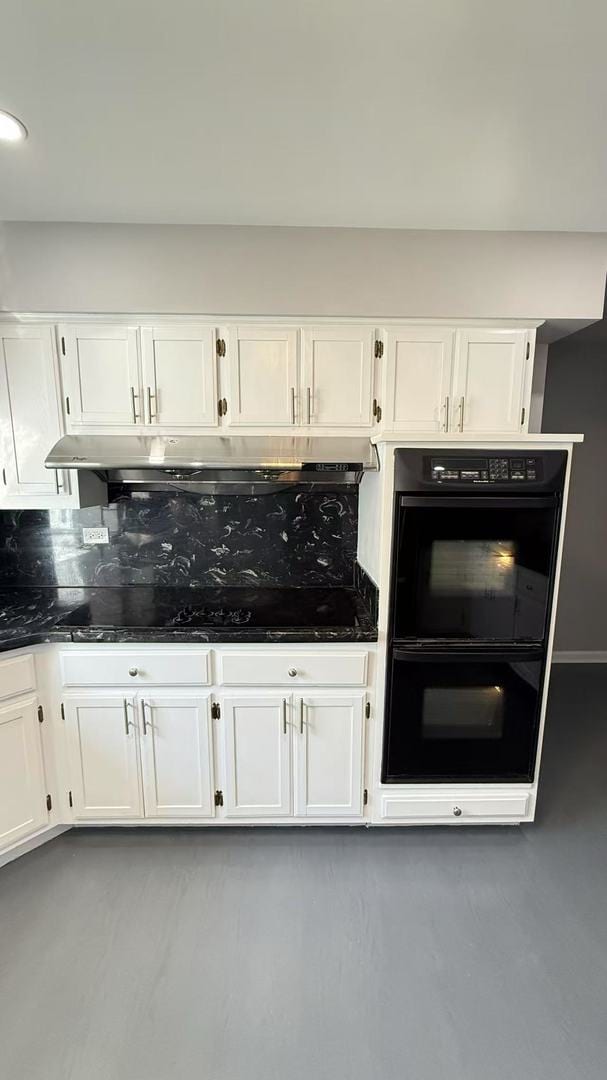 kitchen with black appliances, under cabinet range hood, backsplash, and white cabinets