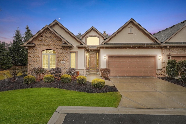 view of front of property featuring concrete driveway, an attached garage, brick siding, and stucco siding