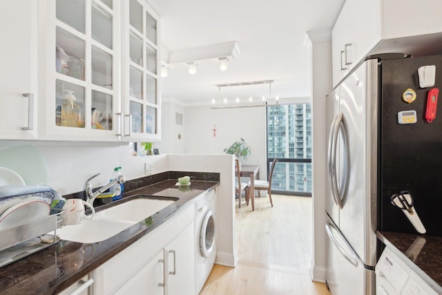 kitchen with light wood finished floors, glass insert cabinets, ornamental molding, washer / dryer, and freestanding refrigerator