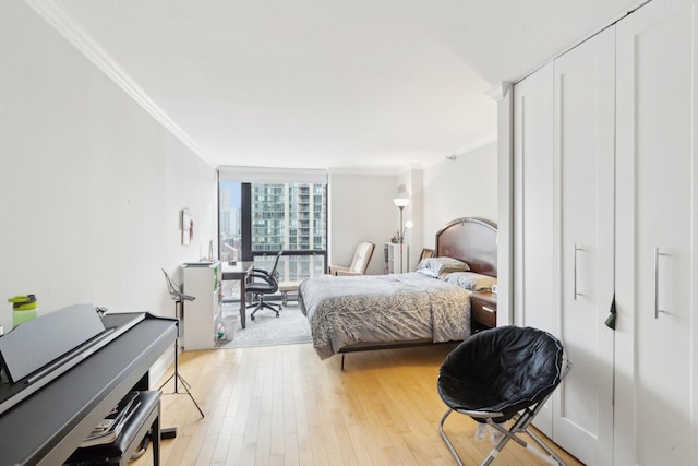 bedroom with floor to ceiling windows, light wood-style flooring, and ornamental molding