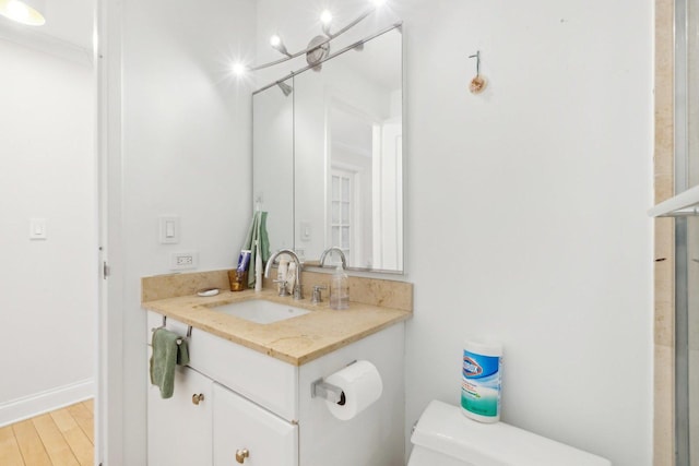 bathroom featuring vanity, toilet, wood finished floors, and baseboards