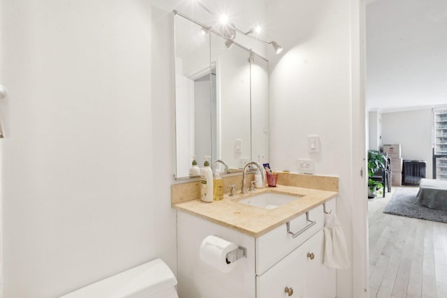 half bathroom with toilet, vanity, and wood finished floors