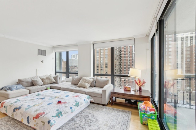 living room featuring a wall of windows, wood finished floors, visible vents, ornamental molding, and a view of city