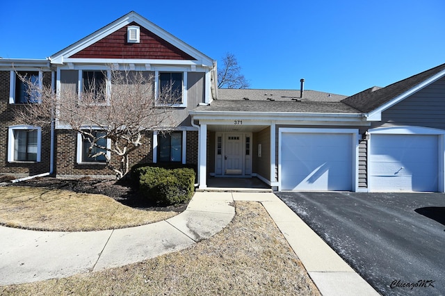 traditional-style house with a garage, driveway, brick siding, and a shingled roof