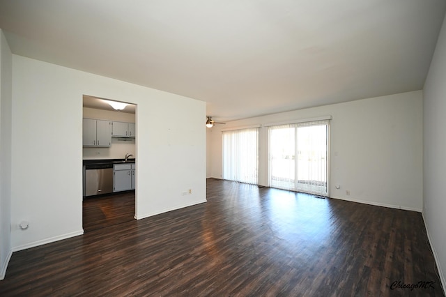 unfurnished living room featuring a sink, ceiling fan, baseboards, and dark wood-style flooring