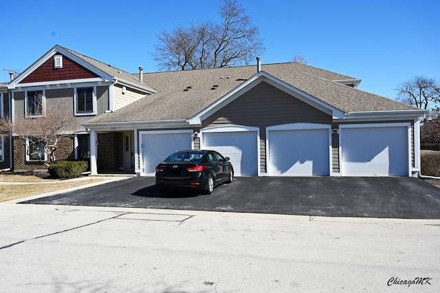 view of front of property featuring driveway, a shingled roof, and an attached garage