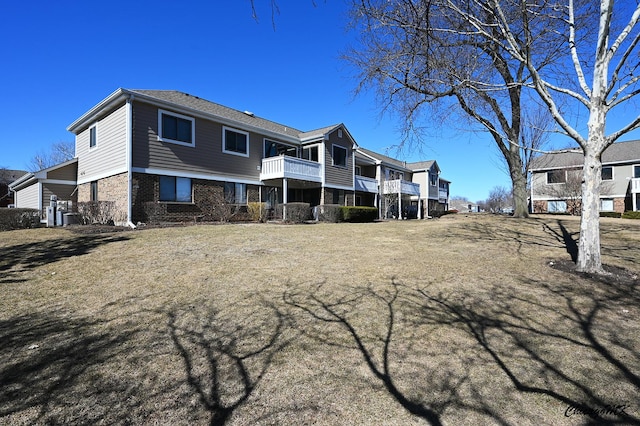 back of property featuring a balcony and brick siding