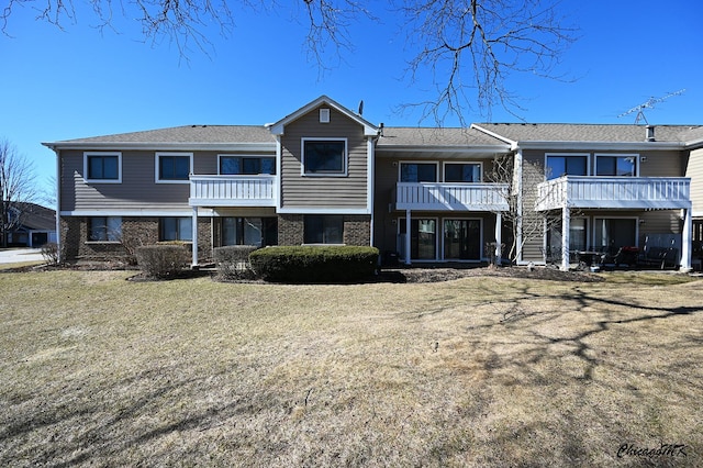 back of house featuring brick siding and a yard