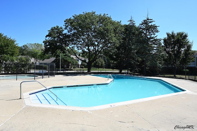 community pool with a patio area and fence