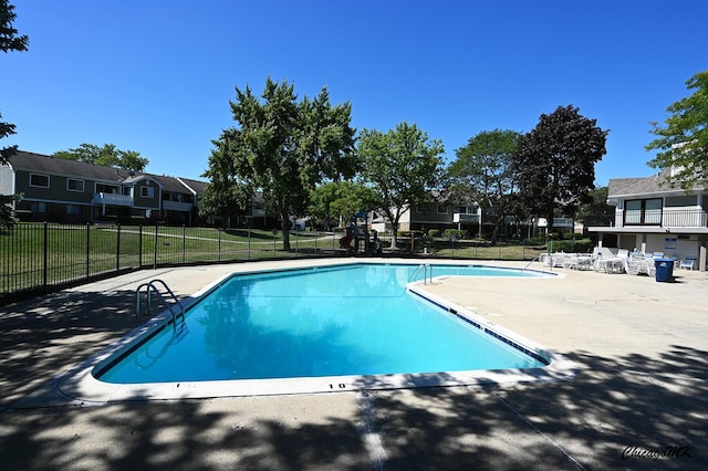 pool with a patio area, fence, and a residential view