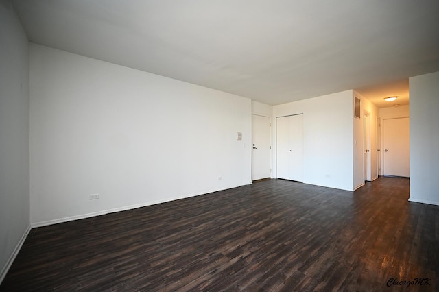 spare room featuring dark wood-type flooring and baseboards