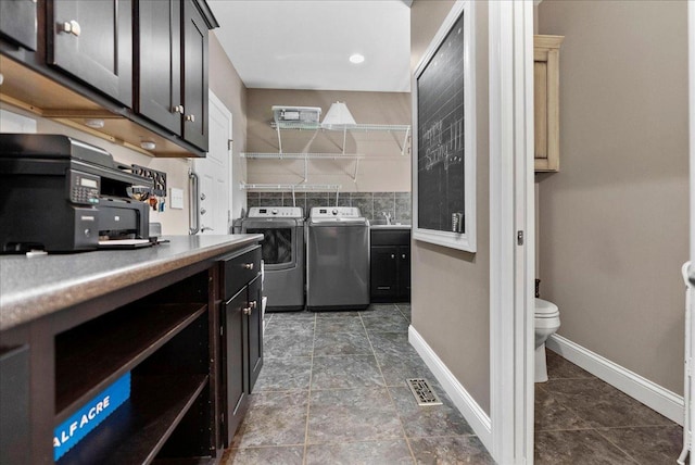 washroom with visible vents, independent washer and dryer, baseboards, and a sink