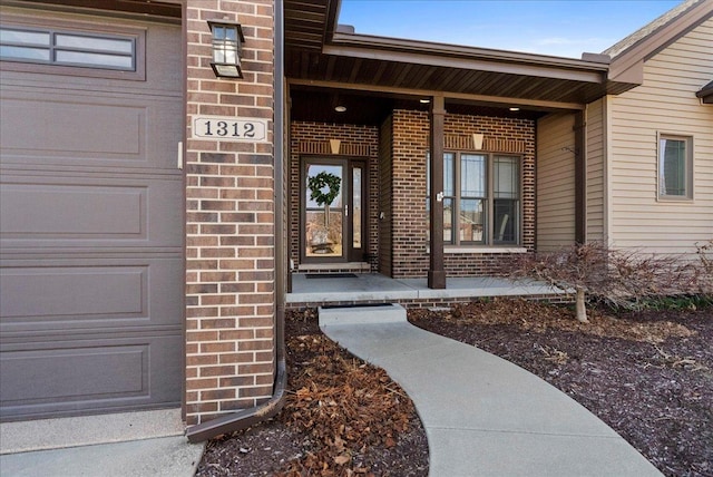 view of exterior entry with brick siding and covered porch